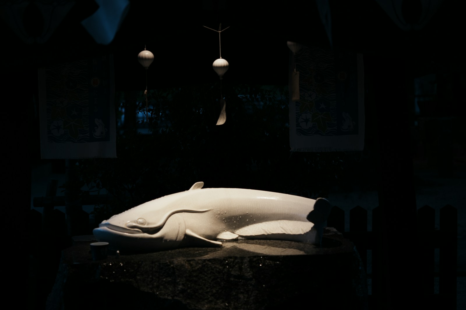A white whale sculpture on a dark stand with hanging ornaments